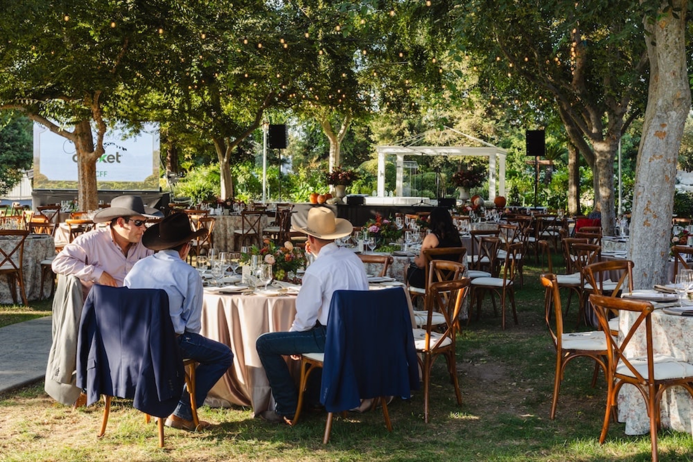 Guests at an outdoor garden dinner at a past Hand to Harvest gala