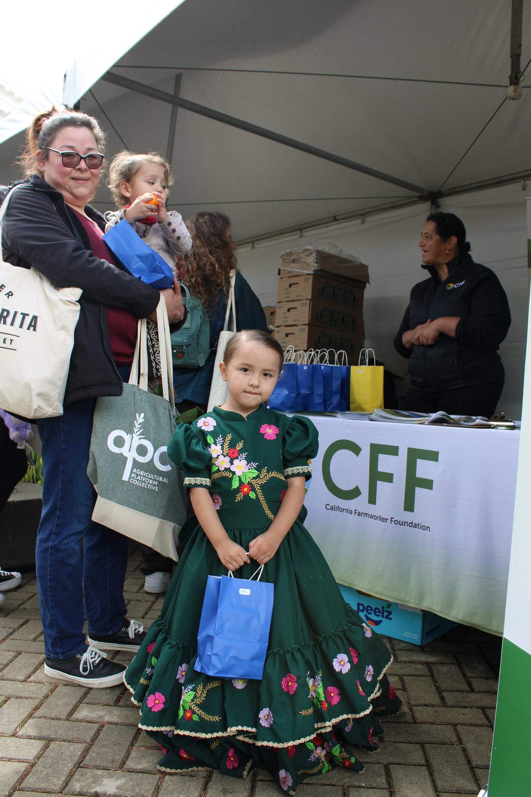 A family visiting the California Farmworker Foundation booth at a community event