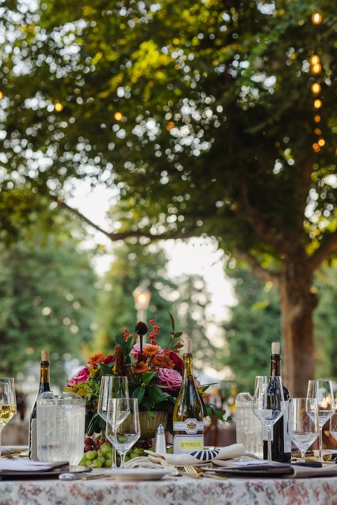 A candlelit garden dinner table set with wine, flowers, and string lights at a past Hand to Harvest gala